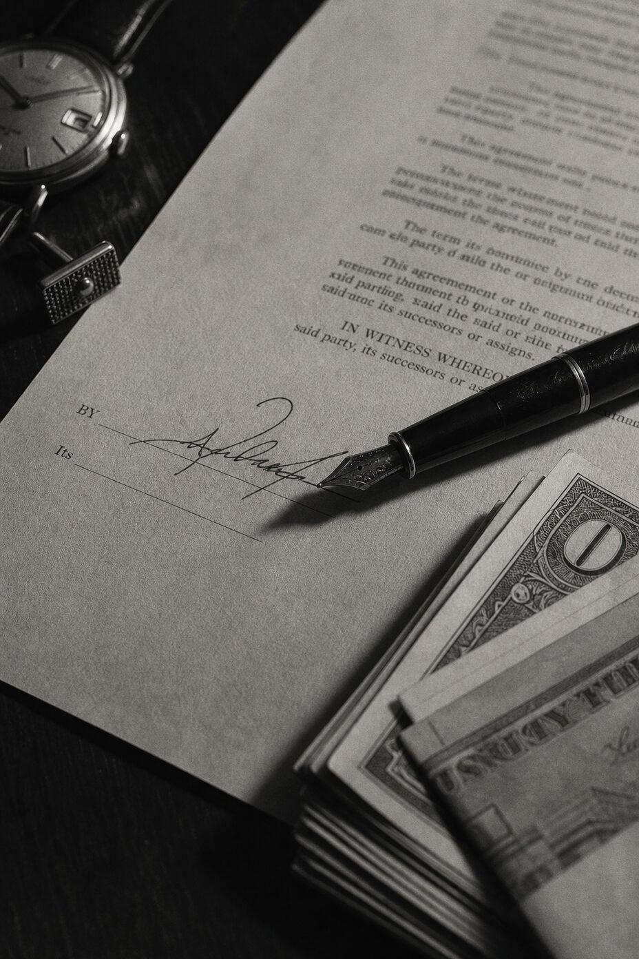 A document bearing four signatures beside a sum of cash on a table