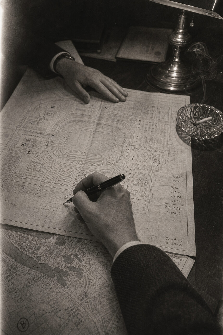 Maps of stadiums spread across a table, marked with capacity figures and sightlines